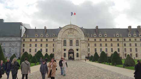 Façade-of-Les-Invalides-in-Paris-with-Tourists-and-Parisians-Walking-through-Central-Entrance