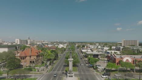 An-aerial-establishing-shot-zooms-in-on-The-Monument-of-Heroes-on-Broadway-in-Galveston,-Texas