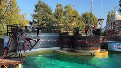 Acrobats-diving-in-amusement-water-park-pool-from-swing-swinging
