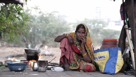 Una-Mujer-Filmada-En-La-Calle-Está-Preparando-La-Cena-Para-Su-Familia-En-La-Acera-Y-Está-Mirando-A-La-Cámara.