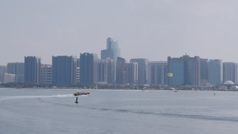 Abu-Dhabi-Uae-Wasser-Und-Stadtbild-Skyline,-Schnellboot-Und-Parasailing-Fallschirm,-Weite-Sicht