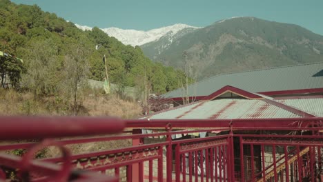 Rote-Brücke-Mit-Blick-Auf-Die-Berge-Im-Hintergrund,-Sonniger-Tag,-Heitere-Atmosphäre,-Außenaufnahme