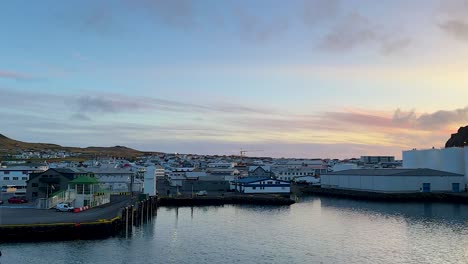 Wide-pan-of-fishing-harbor-at-Westman-Islands-in-Iceland-at-sunset,-from-water