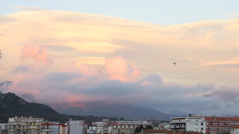 Wunderschöne-Aussicht-Auf-Ajaccio-Bei-Sonnenuntergang,-Vögel-Fliegen-Im-Himmel-Mit-Bunten-Wolken
