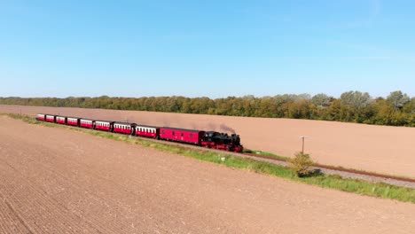 Aerial:-steam-narrow-gauge-railway-in-the-countryside-passing-by-sown-fields