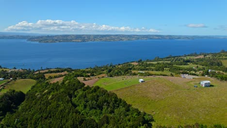 Aerial-Flyover-Green-Hill-And-Los-Brujos-Dock,-Lemuy-Island,-Chiloe,-Chile-4K-Drone