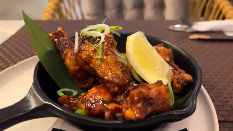 Teriyaki-chicken-wings-with-spring-onion-and-a-lemon-slice,-delicious-Asian-cuisine,-4K-shot