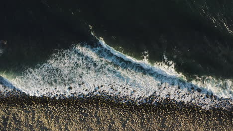 Bird's-eye-zoom-in-over-Pacific-Ocean-waves-breaking-on-rocky-shore,-Oregon-Coast