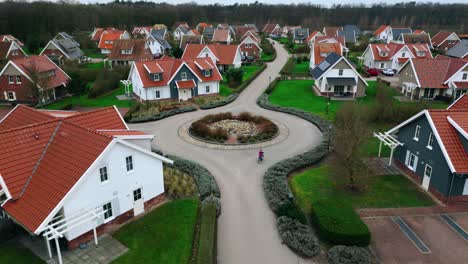 Child-biking-in-luxurious-real-estate-bungelow-park-aerial-top-view-moving-forward