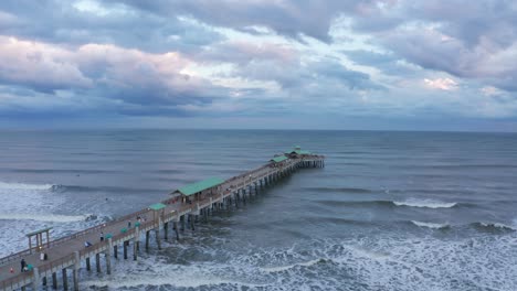 Toma-Aérea-Panorámica-Baja-Del-Muelle-En-Folly-Beach-En-Folly-Island-Al-Atardecer-En-Carolina-Del-Sur