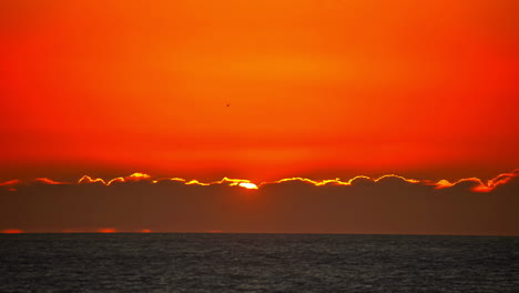 Massive-red-sunrise-over-ocean-horizon,-time-lapse-view