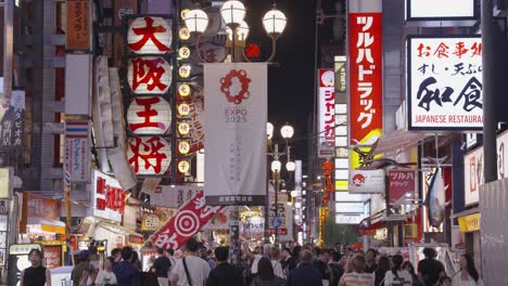 Tight-shot-of-signs,-lights-and-crowds-waking-through-busy-tourist-street-Osaka,-Chuo-Ward,-Dotonbori-Japan