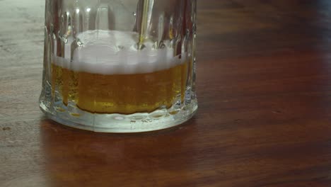 Golden-amber-beer-is-poured-into-glass-on-counter,-close-up-view