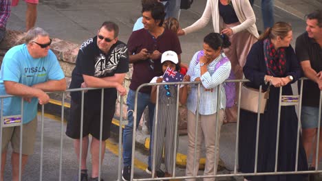 People-gather-along-the-street,-anticipating-for-the-start-of-the-annual-Anzac-Day-parade-tradition-at-Brisbane-city,-waving-the-national-flag,-close-up-shot