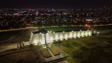 Facade-of-Columbus-Lighthouse-in-Santo-Domingo-lit-up-at-nigh,-high-drone-view