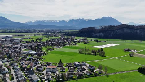 Oberriet-En-Suiza-Con-Exuberantes-Campos-Verdes-Y-Fondo-De-Los-Alpes,-Día-Soleado,-Vista-Aérea