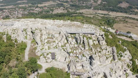 Retreating-drone-shot-panning-slowly-to-the-right,-showing-the-whole-stretch-of-the-ancient-city-of-Perperikon-situated-on-a-hilltop-in-the-province-of-Kardzhali-in-Bulgaria