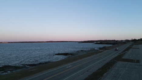 Car-drives-along-ocean-avenue-in-Newport-Rhode-Island-at-Sunrise