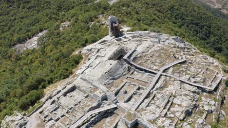 Drone-approaching-the-ancient-historical-landmark-of-Perperikon,-revealing-a-water-reservoir-and-a-tower-at-the-edge-of-the-palace-complex,-located-in-Kardzhali-province-in-Bulgaria