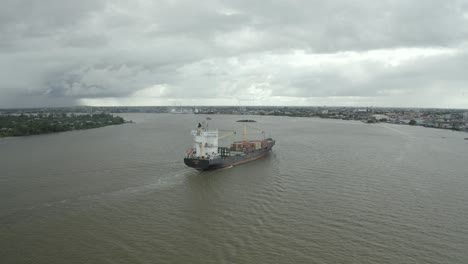 Cargo-ship-sailing-in-the-Suriname-river-towards-harbor,-drone-view-panning-around