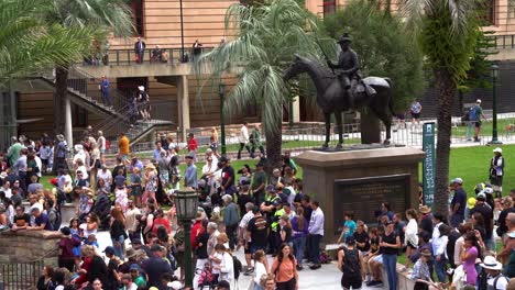 Grandes-Multitudes-De-Personas-Se-Reúnen-En-El-Centro-De-La-Ciudad-De-Brisbane,-Llenas-De-Anticipación-Antes-Del-Comienzo-Del-Tradicional-Desfile-Anual-Del-Día-De-Anzac-En-La-Plaza-Anzac.