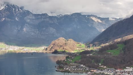 Drone-shot-over-the-Walensee-in-Unterterzen-Mols-in-Switzerland---lakeshore-with-houses-and-high-mountains-in-the-background