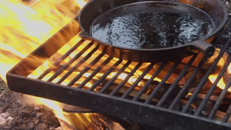 Cast-iron-pan-with-removable-handle-is-seasoned-with-oil-on-open-fire