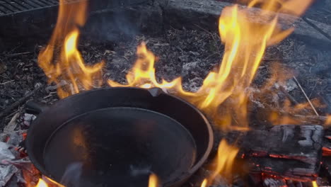 Große-Eiserne-Bratpfanne-Wird-Direkt-Auf-Die-Flammen-Eines-Lagerfeuers-Im-Freien-Gestellt