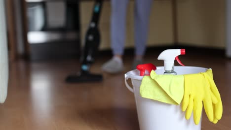 4k-video-footage-detergents-in-a-bucket-on-the-floor-and-woman-cleaning-her-home-in-the-background