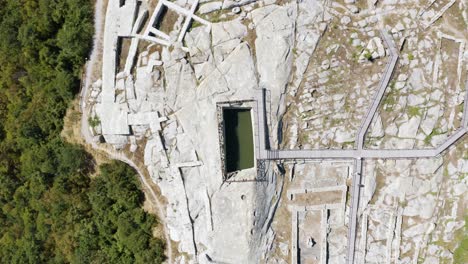 Overhead-drone-shot-of-a-water-reservoir-situated-in-the-middle-of-the-complex-of-the-historical-landmark-of-Perperikon,-in-the-province-of-Kardzhali-in-Bulgaria