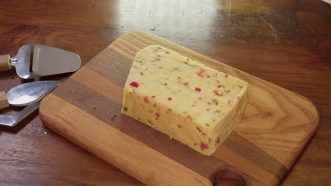 Smoked-gouda-cheese-with-spicy-red-peppers-is-sliced-on-cutting-board