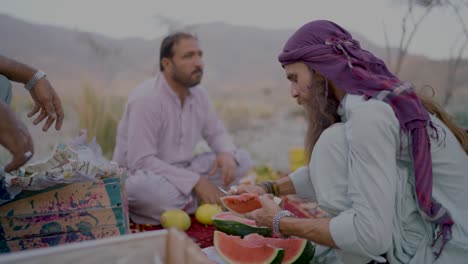 Long-bearded-Pakistani-man-cutting-watermelon-for-ramadan-iftar-in-Khuzdar,-Balochistan,-Pakistan