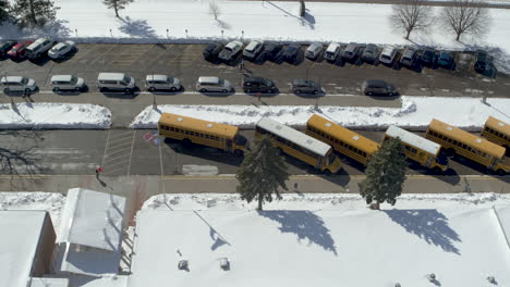 Luftaufnahme-Von-Schulbussen-Auf-Einem-Verschneiten-Parkplatz-Einer-Grundschule-Im-Winter