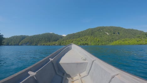 Bow-of-boat-sailing-toward-island-on-Kali-Biru-blue-river-of-Raja-Ampat-archipelago-in-Indonesia