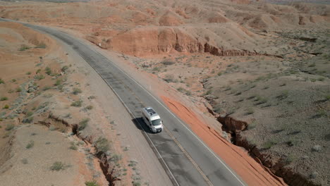 Rearwards-tracking-shot-of-an-RV-driving-along-a-quiet-road-in-the-desert
