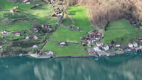 Drone-shot-over-Lake-Walen-in-Quinten-in-Switzerland---Lakeshore-with-houses-and-vineyards