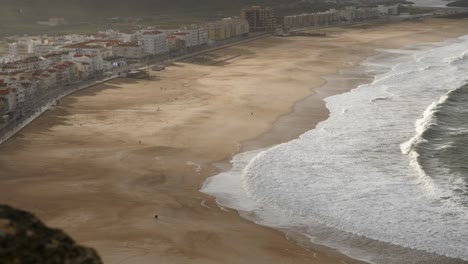 Playa-Praia-Da-Nazaré-En-La-Hora-Dorada-Con-Sombras-Tomadas-Desde-Arriba-En-4k-Con-Gente-Distante-Caminando-Por-La-Playa