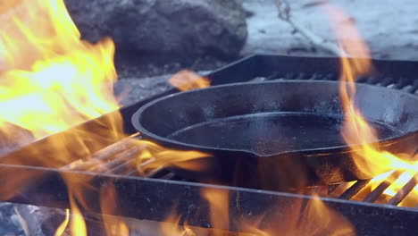 Oiled-cast-iron-pan-placed-onto-open-fire-grill-to-season-the-utensil