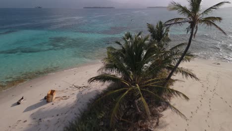 Drone-shot-of-a-remote-island-and-a-couple-paddling-in-the-background-in-San-Blas-Islands,-Panama