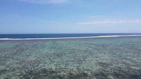 Drone-footage-along-the-Coral-Coastline-in-Fiji,-capturing-the-intricate-interface-between-the-vibrant-coral-reefs-and-the-vast-ocean