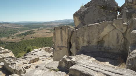 Panning-from-the-left-to-the-right-side-of-the-frame,-showing-the-rock-structures-of-the-ancient-city-of-Perperikon-and-the-valley-below-in-the-province-of-Kardzhali-in-Bulgaria