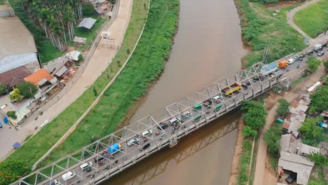 Aerial-view-drone-footage-overhead-shot-above-the-Citarum-bridge-over-the-Citarum-river-in-Bandung,-Indonesia,-with-traffic,-cars-and-trucks,-crossing-in-morning-light
