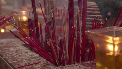 Close-up-shot-hands-lighting-Chinese-red-incense-prayer-sticks-fire-and-smoke-inside-at-china-temple