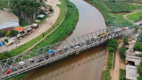 Luftaufnahme-Einer-Drohnenaufnahme-über-Der-Citarum-Brücke-über-Dem-Citarum-Fluss-In-Bandung,-Indonesien,-Mit-Verkehr,-Autos-Und-Lastwagen,-Die-Im-Morgenlicht-überqueren