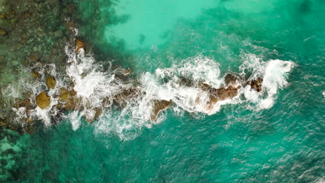 Turquoise-ocean-water-crashing-on-surface-rock-and-coral