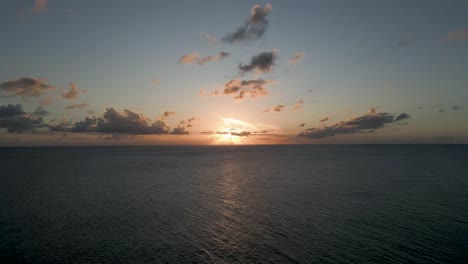 Sunset-on-horizon-Aerial-Drone-Shot-center-frame-with-clouds-and-calm-Caribbean-ocean-water