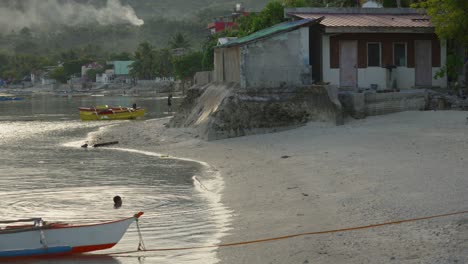 Tropischer-Strand-Auf-Den-Philippinen-Mit-Einem-Einheimischen-Kind,-Das-Im-Meer-Schwimmt,-Und-Rauchigen-Bergen-Im-Hintergrund