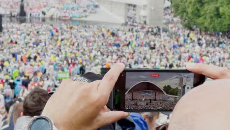 13.-Jugendsänger--Und-Tanzfest-–-„Heilig-Ist-Das-Land“,-Mann-Filmt-Sängerfest-Mit-Handy