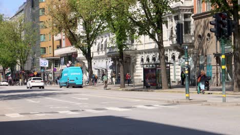 Tráfico-De-Bicicletas-Y-Automóviles-En-Una-Calle-Arbolada-En-El-Centro-De-Estocolmo,-Un-Día-Soleado-De-Verano