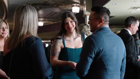 A-Young-with-Tattoos-in-an-elegant-ball-gown-dress-talks-with-people-smiles-and-laughs-at-a-fancy-evening-event